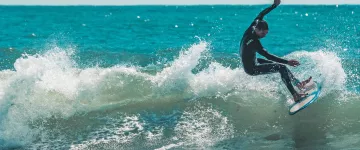 Surfear en la playa de Les Huttes